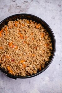 Die Streusel als Topping dann über die Aprikosen verteilen